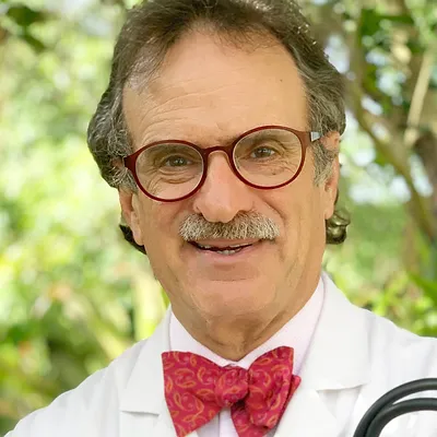 A portrait of Dr. Mandel Sher with a red bowtie.
